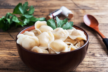 Traditional pelmeni, ravioli, dumplings filled with meat on plate, russian kitchen. Wooden rustic background, copy space.