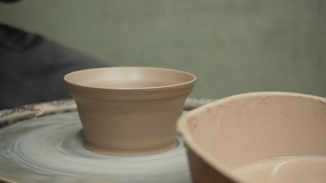 A cup, pot or deep plate is dried with a construction hairdryer on a pottery circle during rotation