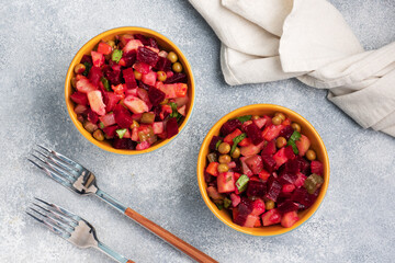 Vinaigrette with beetroot and boiled vegetables, traditional Russian homemade salad. Serving bowls with a cold snack on the table, copy space.
