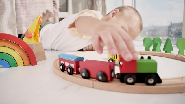 Boy plays with a wooden train. Sunny day. Montessori material education. Toy is natural zero waste. Copy space