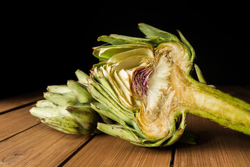 Artichoke (globe, French or green), raw uncooked on a wooden table. 