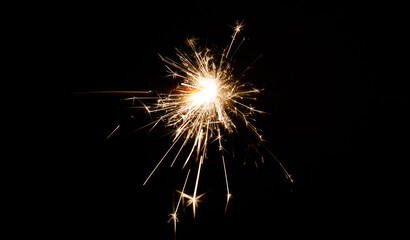 New Year's Eve celebration with a sparkler, isolated on black background. - obrazy, fototapety, plakaty