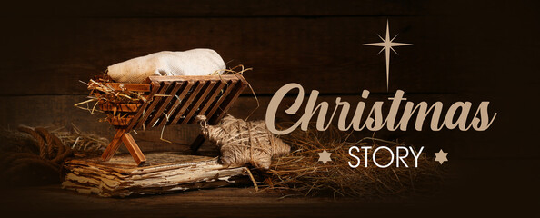 Manger with baby and old book on wooden background. Concept of Christmas story