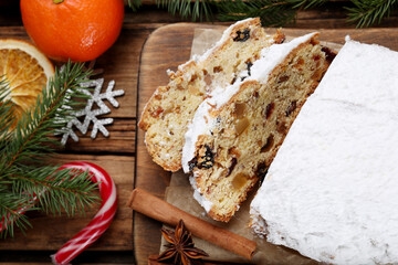 Obraz na płótnie Canvas Traditional Christmas Stollen with icing sugar on wooden table, flat lay