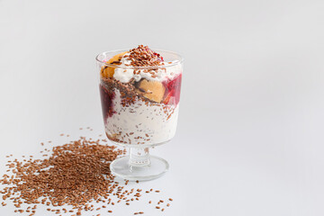 Tasty dessert with flax seeds and yoghurt in glass on light background