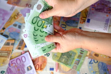 closeup female hands count paper 100 euro banknotes of european union, paper banknotes on table,...