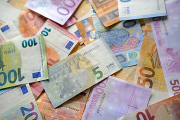 closeup paper 5,100, 50 euro banknotes of european union against background of scattered paper banknotes on table, concept of payments, savings, banking, save up for vacation, cash out currency