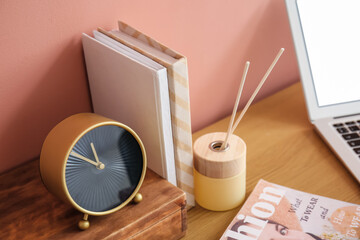 Stylish workplace with golden alarm clock on table near wall