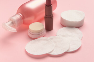 Obraz na płótnie Canvas Lotion bottle, lipstick and cotton pads on pink table, closeup
