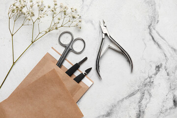 Paper bag with manicure equipment and flowers on white background