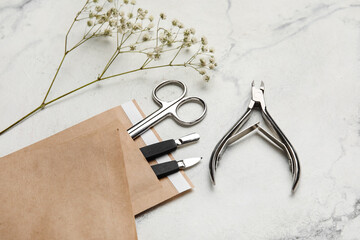 Paper bag with manicure equipment and flowers on white background, closeup