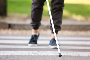 Blind man crossing road in city