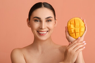 Beautiful smiling woman holding cut mango on color background