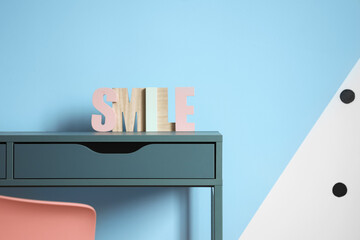 Word SMILE on table near color wall