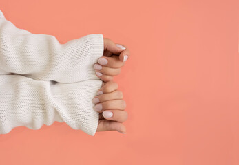 Well-groomed women's hands on a pink background, gentle manicure. 