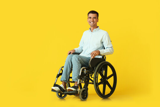 Young Man In Wheelchair On Color Background