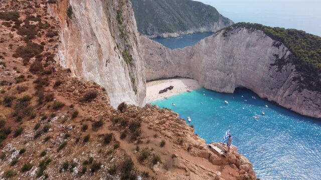 Woman with greek flag on Zakynthos Zante beach coastline. Aerial view