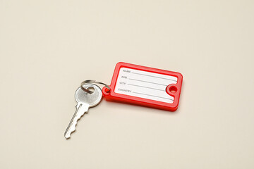 Key with red plastic tag on beige background