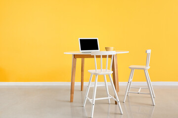 Modern workplace near yellow wall