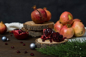 Beautiful red pomegranate fruit composition on a wooden background. Fresh ripe pomegranate selective focus. Pieces and grains of ripe pomegranate