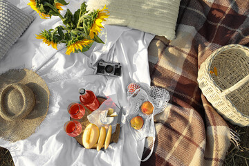 Romantic picnic with tasty food and wine decorated with sunflowers, top view