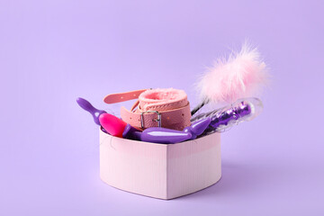 Gift box with different sex toys on color background