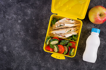 School lunchbox. Healthy lunch box with tortilla wraps stuffed chicken fillet, cheese and tomatoes...