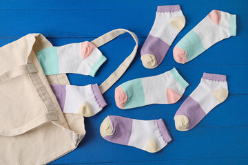 Bag and different socks on color wooden background, closeup