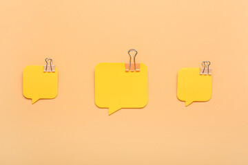 Sticky notes in shape of speech bubbles and binder clips on color background