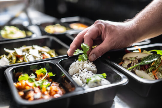 The Chef In Restaurant Kitchen Finishes The Food Ready For Delivery In Takeaway Packages