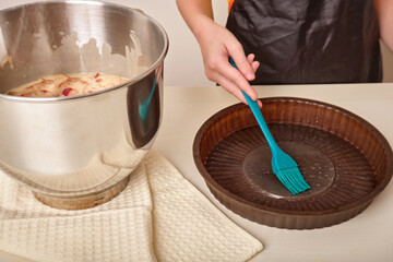 The hand lubricates the baking dish, baking sheet with a brush. The process of making homemade...