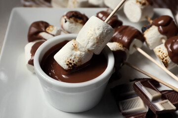 Tasty grilled marshmallows in chocolate on light background