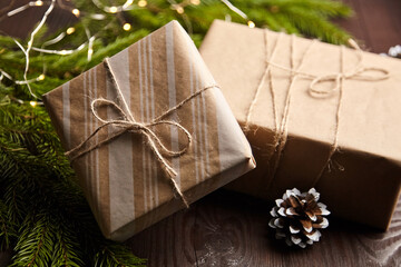 Gift boxes with Christmas light and tree branch with cone on brown wooden