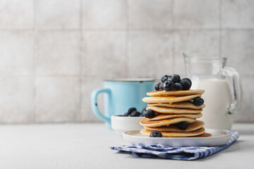 Homemade pancakes with blueberries in stack on light table with tile background