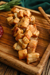 Board with tasty cracklings on wooden background