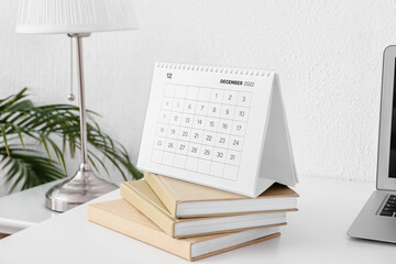 Paper calendar for December 2022 with books at workplace