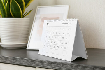 Paper calendar for December 2022 on chest of drawers