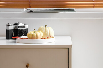 Tray with pumpkins and photo camera on table