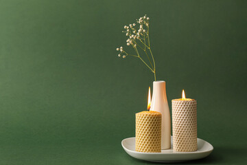 Burning candles and vase with flowers on color background