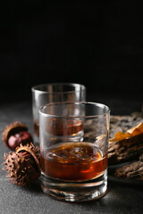 Glasses of cold chestnut whiskey on black background