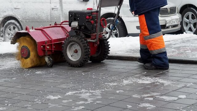 worker removes ice with a snowblower on the sidewalk. Vladivostok, Russia - November 25, 2021.