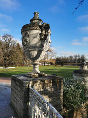 Stone vases of the Elaginoostrovsky Palace with flower beds and a beautiful fence against the background of leafless trees, meadows, rivers and blue sky