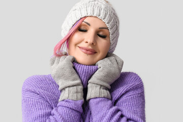 Woman in winter clothes on grey background