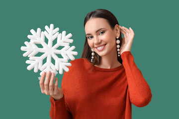 Beautiful woman in pearl earrings with big snowflake on green background