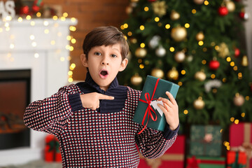 Surprised little boy with gift at home on Christmas eve