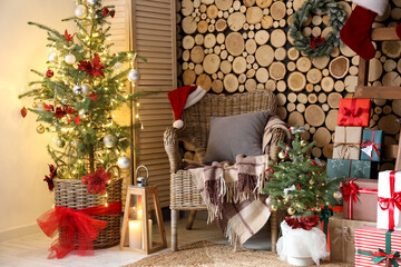 Christmas trees with armchair, ladder and gifts near wooden wall