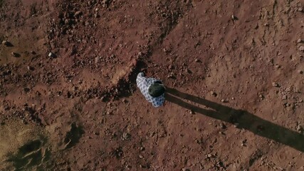 Top view from above . Young man dressed in original costume standing and walking in abandoned land like desert or another planet .  Boy get lost in wasteland . Slow motion . Shot for video clip . 
