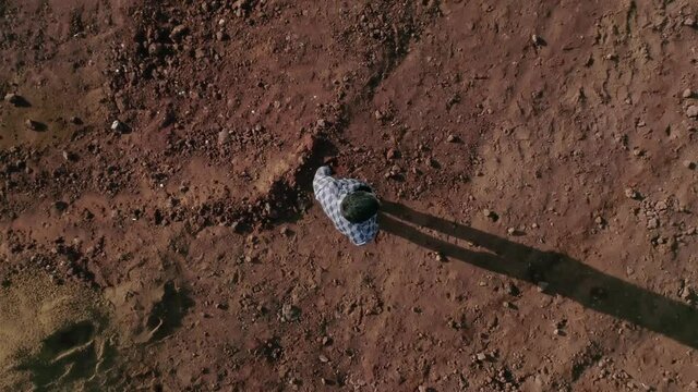 Top view from above . Young man dressed in original costume standing and walking in abandoned land like desert or another planet .  Boy get lost in wasteland . Slow motion . Shot for video clip . 
