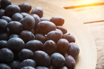 Plate ripe plums in light from window.