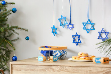 Donuts with dreidels and gifts for Hanukkah celebration on table in room